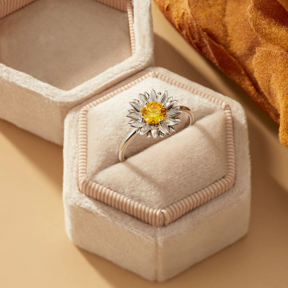 Ring with a yellow gemstone in a hexagonal jewelry box on a beige surface