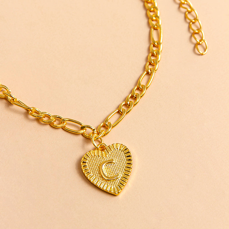 Gold necklace with a heart-shaped pendant letter C on a beige background