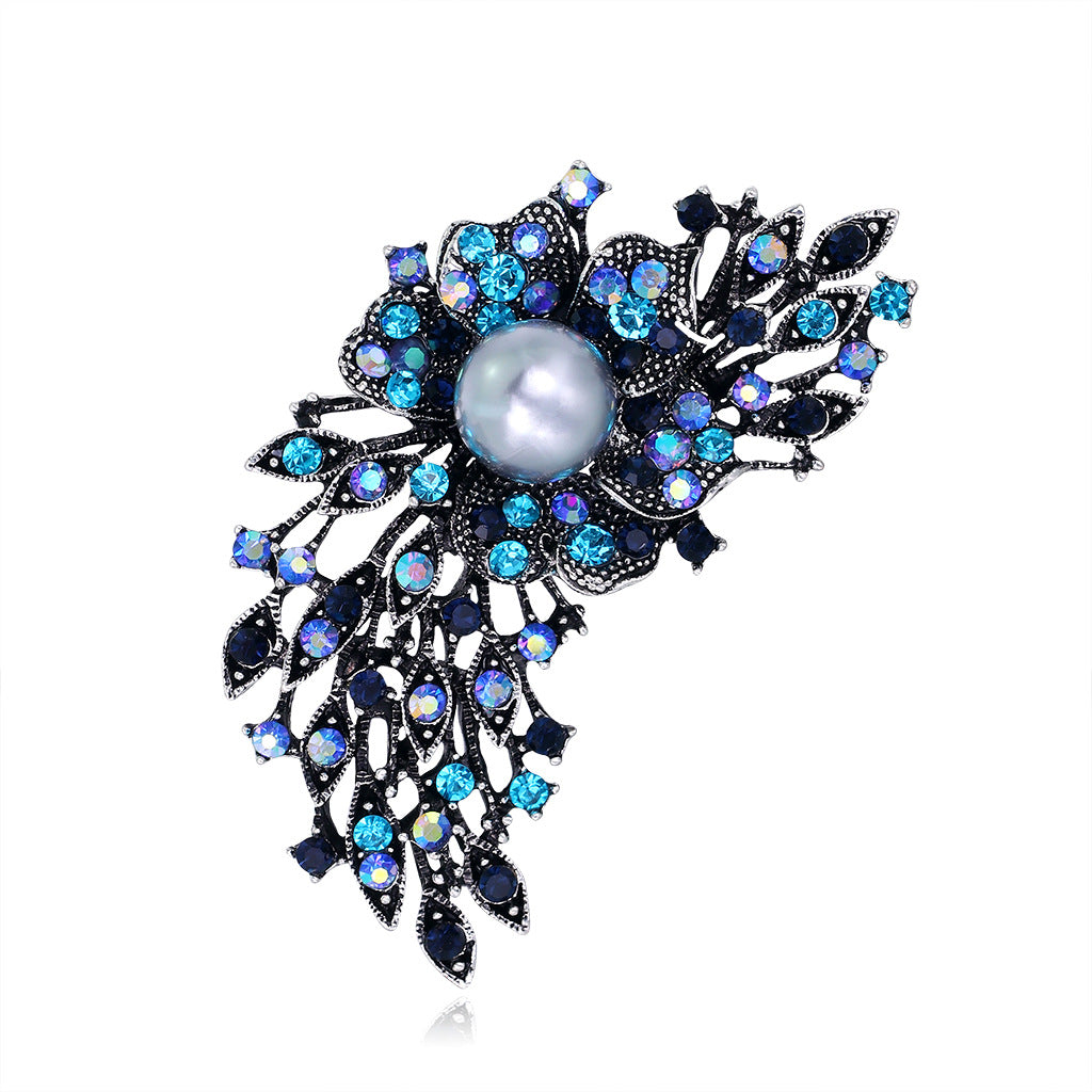 Decorative brooch with blue gemstones and a pearl on a white background