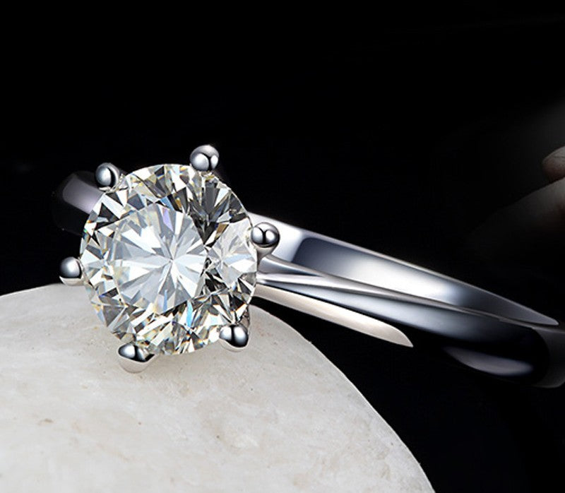 Silver ring with a large diamond on a dark background