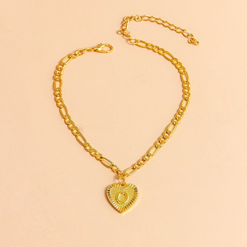 Gold chain necklace with a heart-shaped pendant letter O on a beige background
