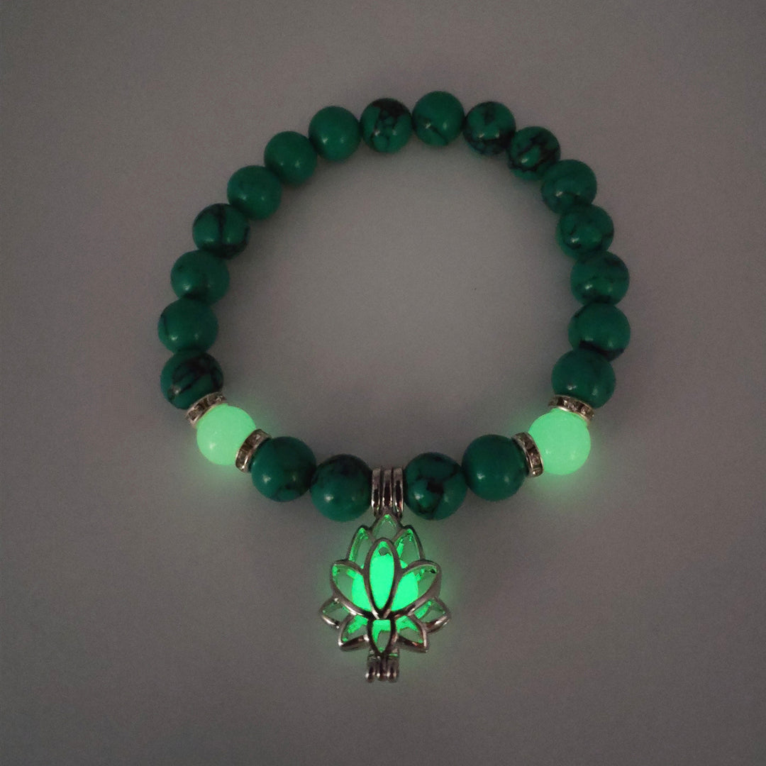 Green beaded bracelet with a glowing leaf charm on a gray background