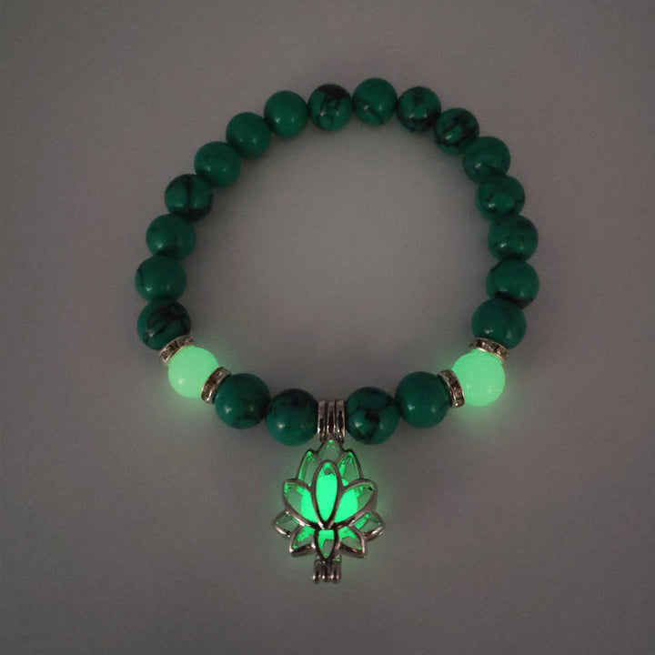 Green beaded bracelet with a glowing leaf charm on a gray background