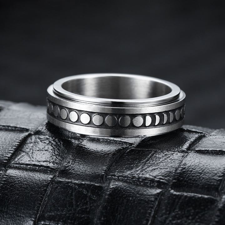 Silver ring with moon phase design on a textured black surface
