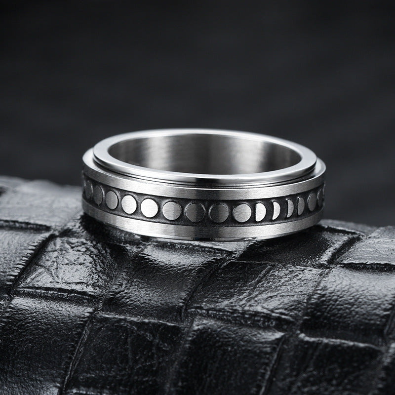 Silver ring with moon phase design on a textured black surface