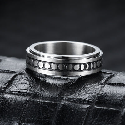 Silver ring with moon phase design on a textured black surface