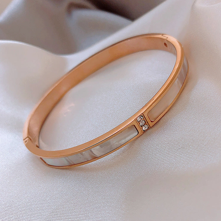 Rose gold bracelet with small diamonds on a light fabric background