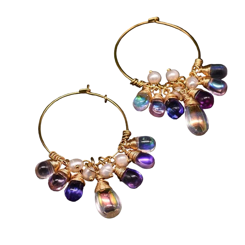 Gold hoop earrings with purple and white bead decorations on a white background