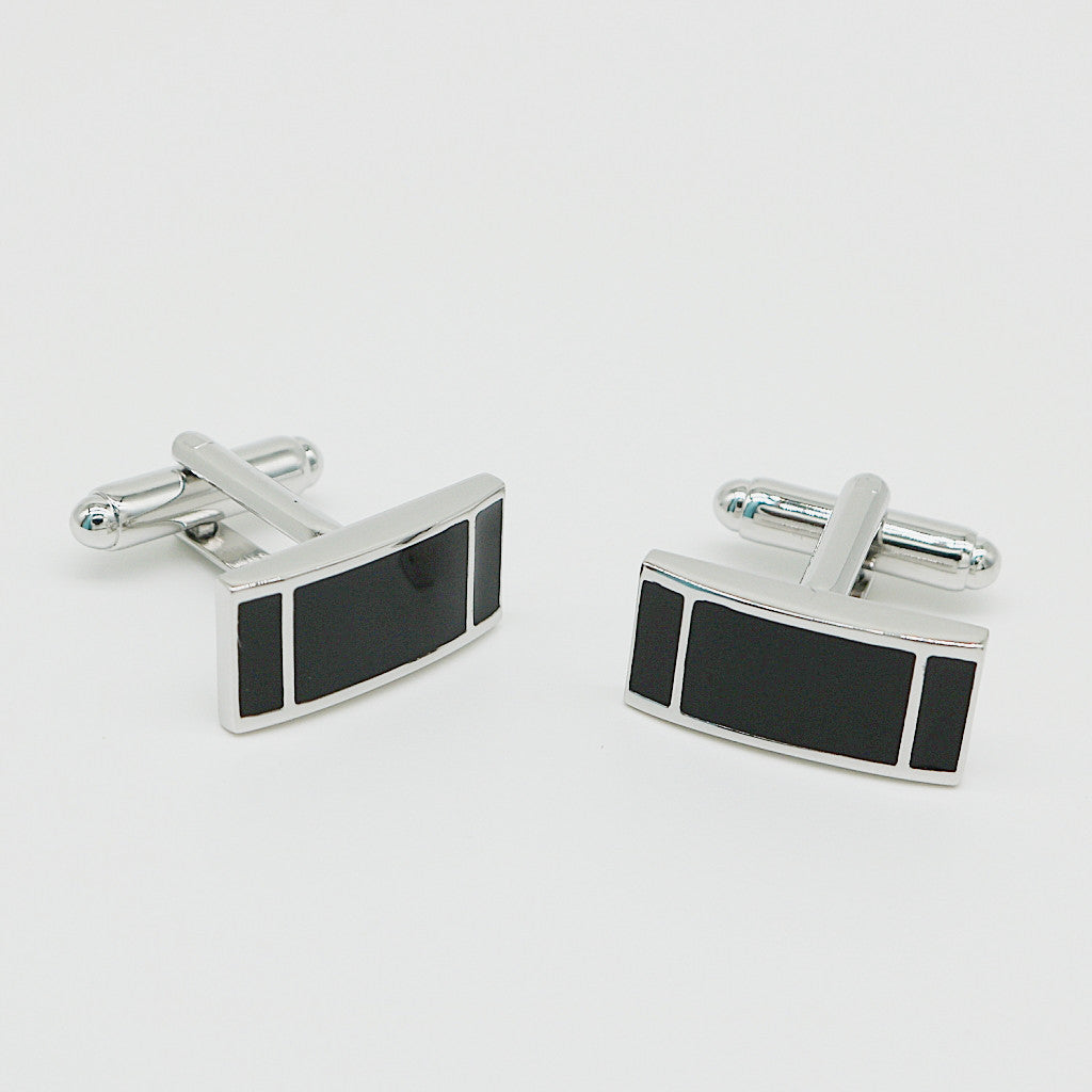 Pair of silver cufflinks with black rectangular stones on a light gray background