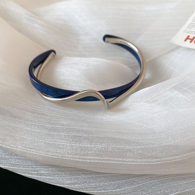 Silver and blue bracelet on a white fabric background