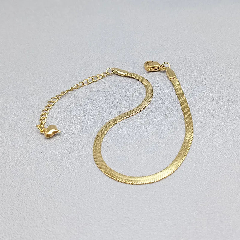 Gold bracelet with heart-shaped ends on a light gray background