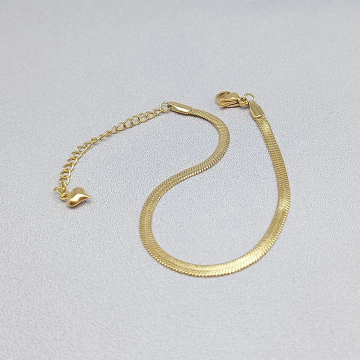 Gold bracelet with heart-shaped ends on a light gray background