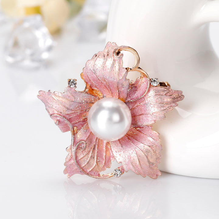 Pink floral brooch with a pearl center on a white background