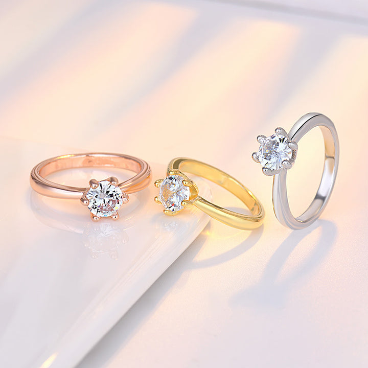 Three diamond rings in rose gold, yellow gold, and white gold on a light background