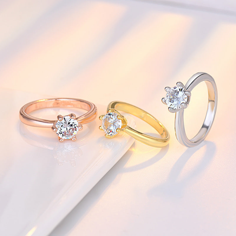 Three diamond rings in rose gold, yellow gold, and white gold on a light background