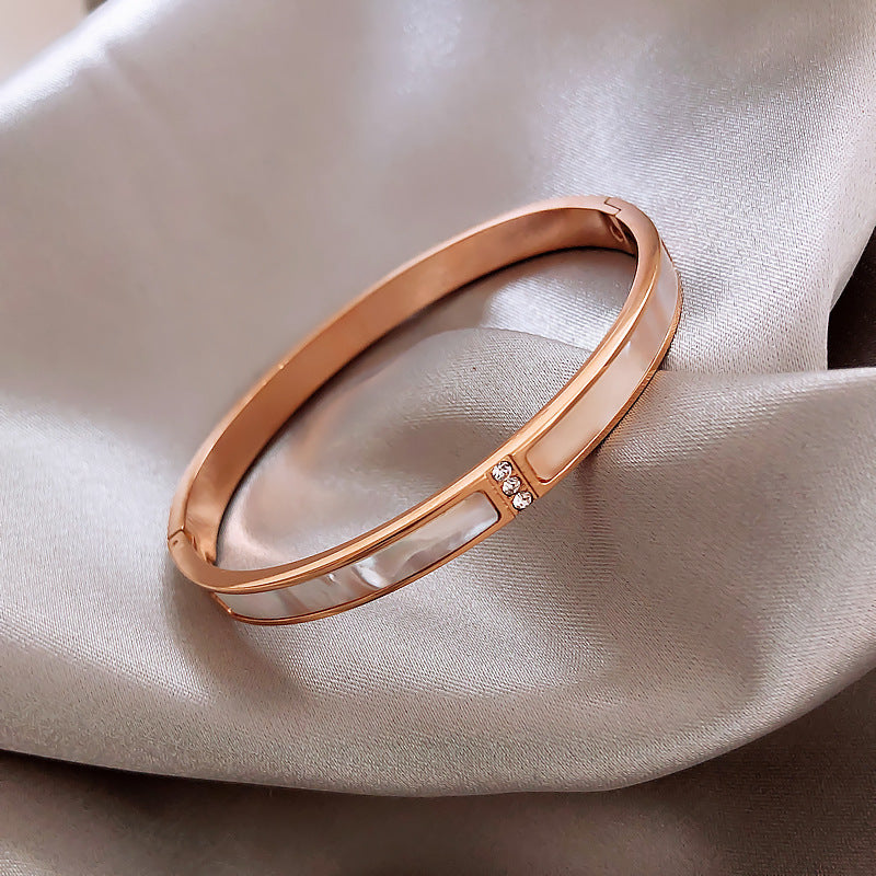 Rose gold bracelet with small diamonds on a beige fabric background