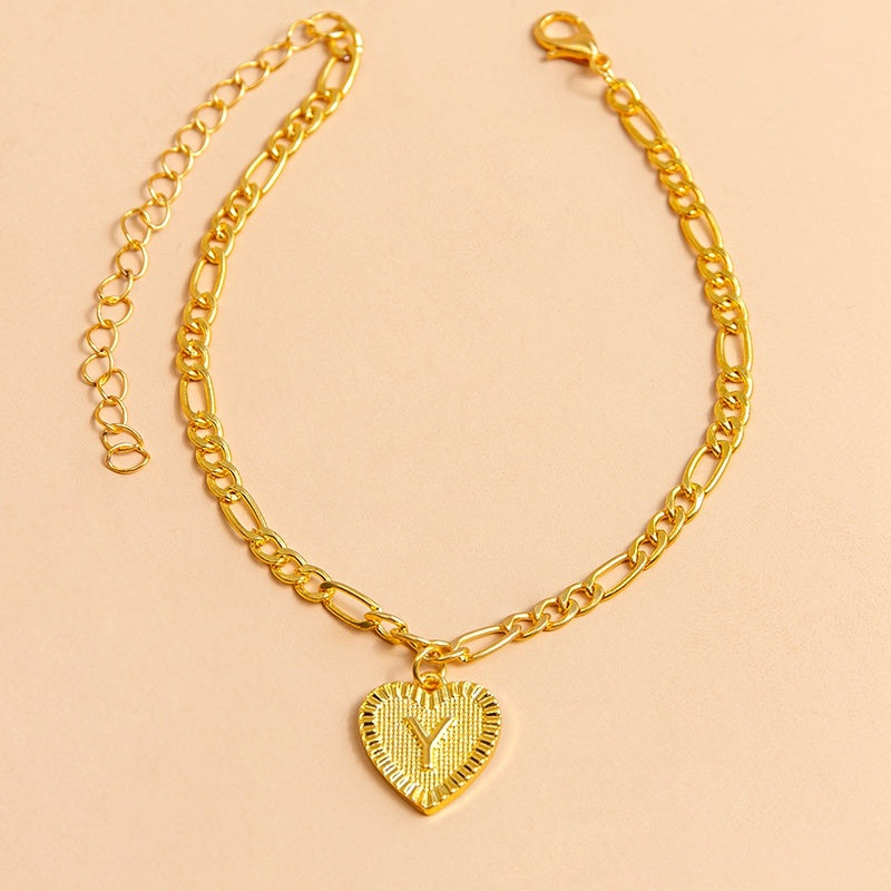 Gold chain bracelet with a heart-shaped pendant letter Y on a beige background