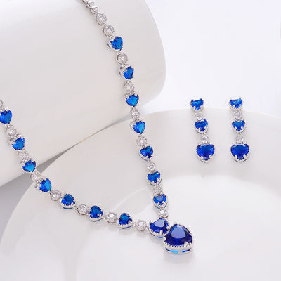 Jewelry set with necklace and earrings featuring blue heart-shaped stones on a white background