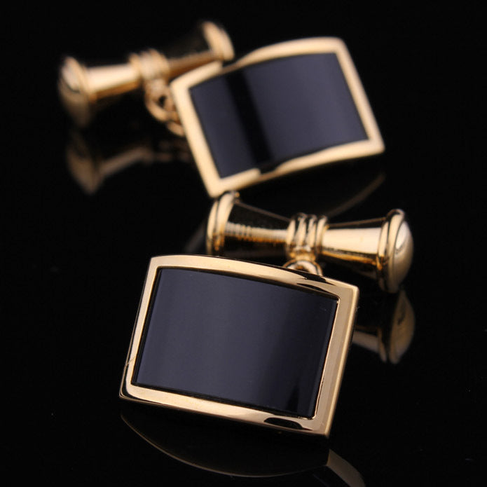 Gold cufflinks with black stones on a black background