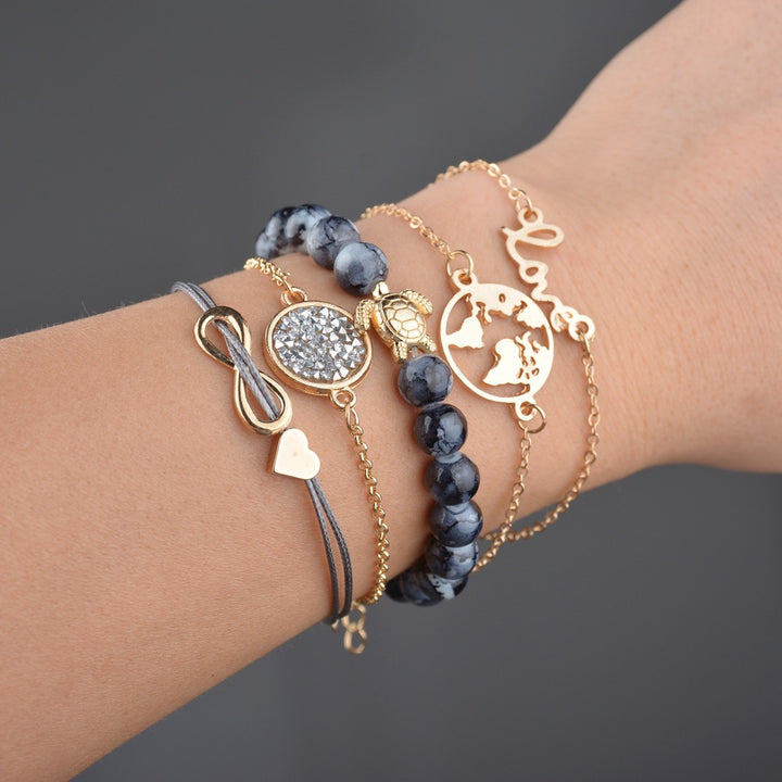 Close-up of a wrist wearing multiple gold and blue beaded bracelets on a dark background