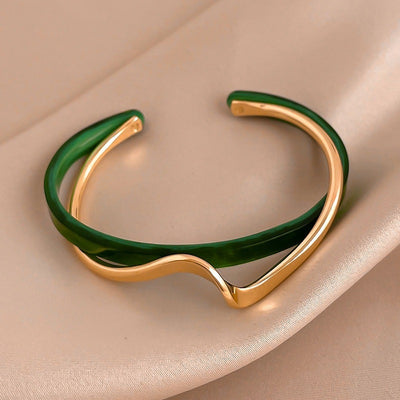 Gold and green bracelet on a beige background