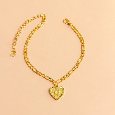 Gold chain bracelet with a heart-shaped pendant letter Q on a beige background