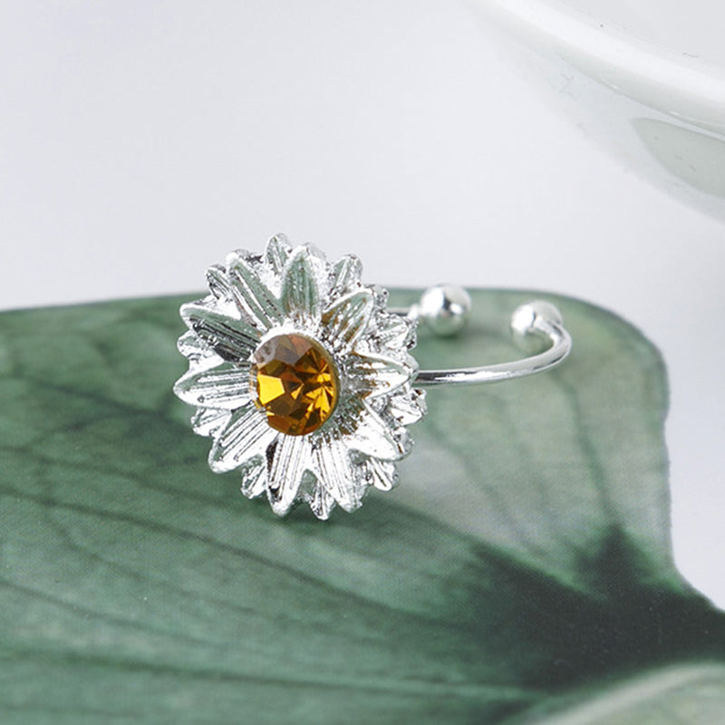 Silver ring with a yellow gemstone on a green leaf