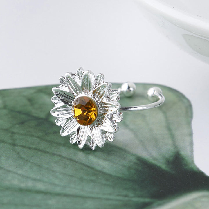 Silver ring with a yellow gemstone on a green leaf