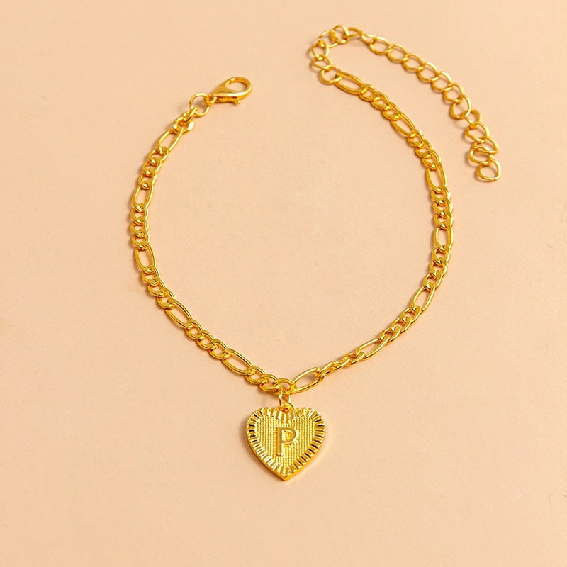 Gold chain bracelet with a heart-shaped pendant letter P on a beige background