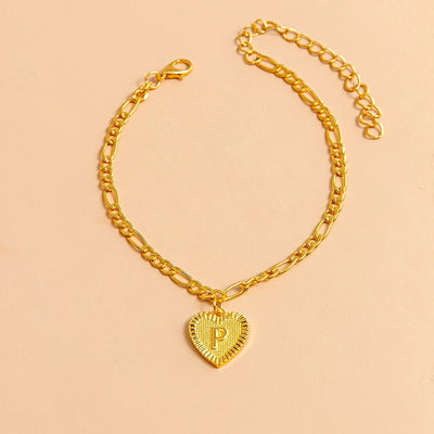 Gold chain bracelet with a heart-shaped pendant letter P on a beige background
