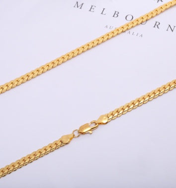 Gold chain necklace on a light gray background with &
