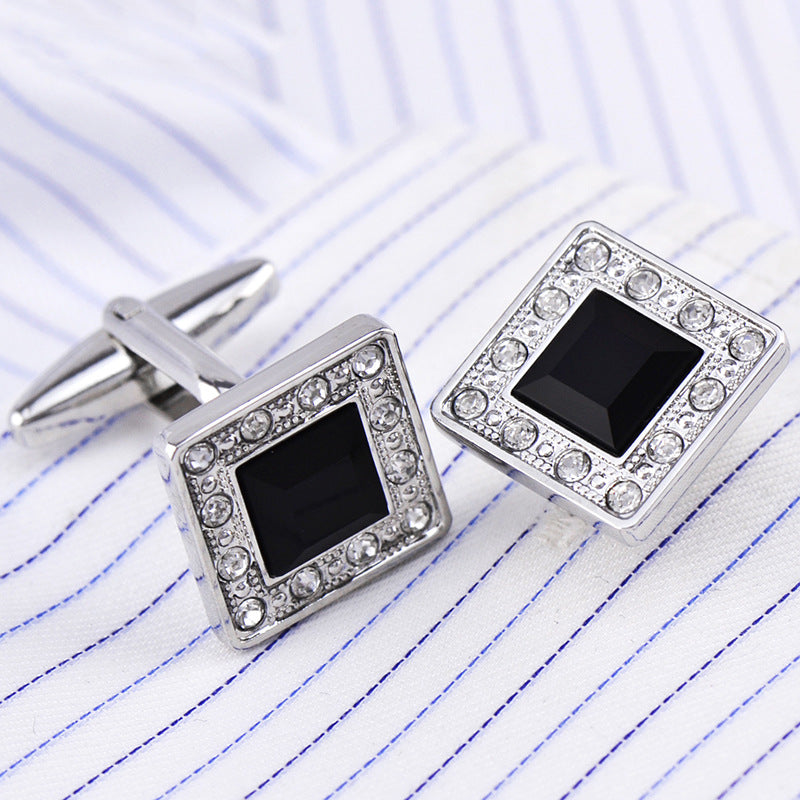 Square cufflinks with black centers and silver borders on lined paper