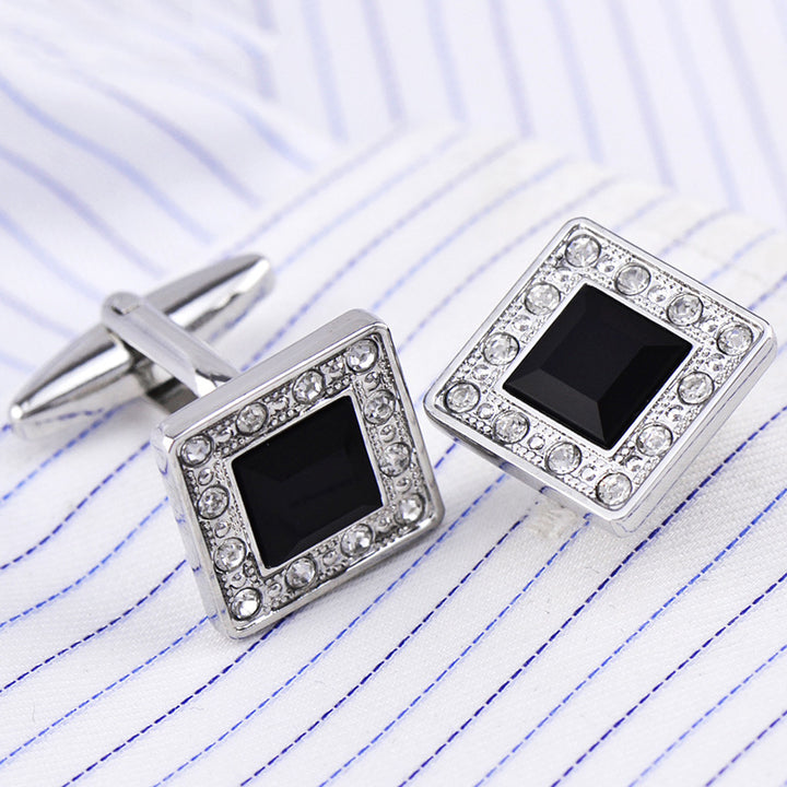 Square cufflinks with black centers and silver borders on lined paper
