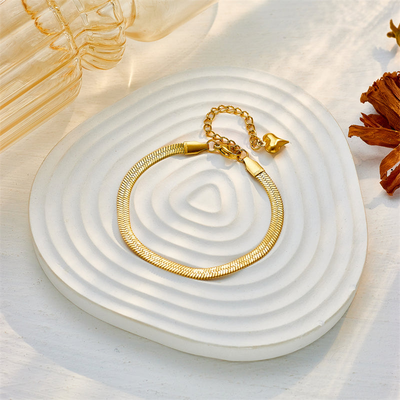 Gold necklace on a white textured surface with a soft focus background