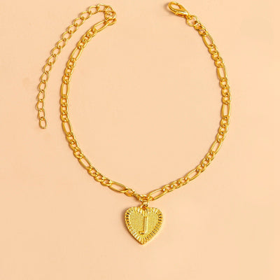 Gold chain necklace with a heart-shaped pendant letter J on a beige background