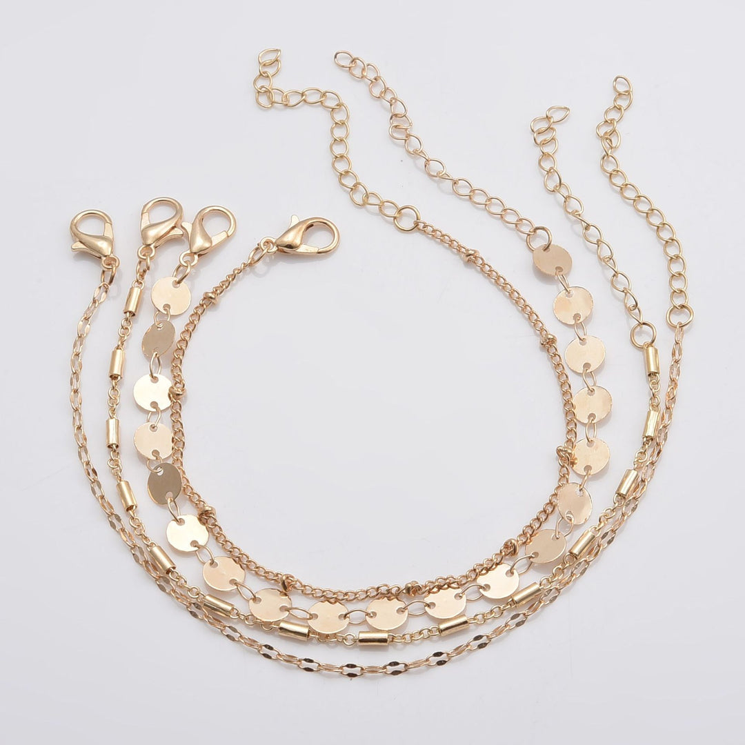four Gold chain bracelet on a light gray background