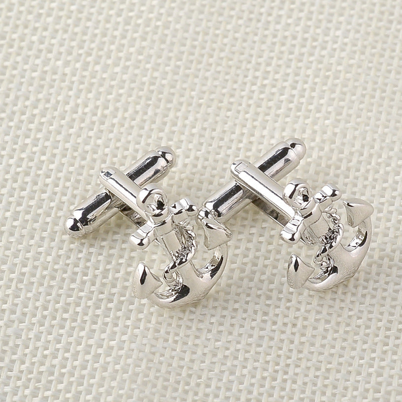 Silver anchor cufflinks on a textured beige background