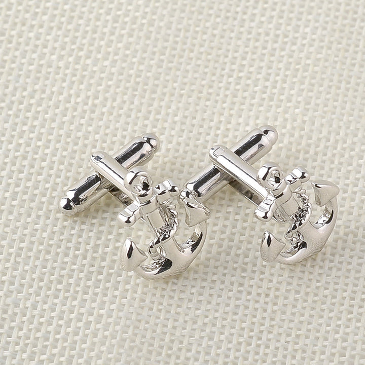 Silver anchor cufflinks on a textured beige background