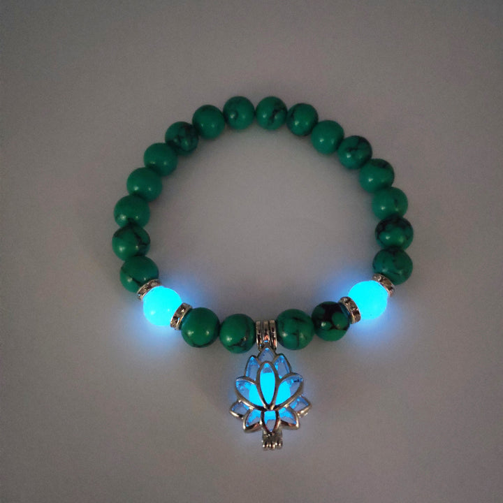 Green beaded bracelet with a glowing pendant on a gray background