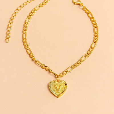 Gold chain necklace with a heart-shaped pendant letter V on a beige background