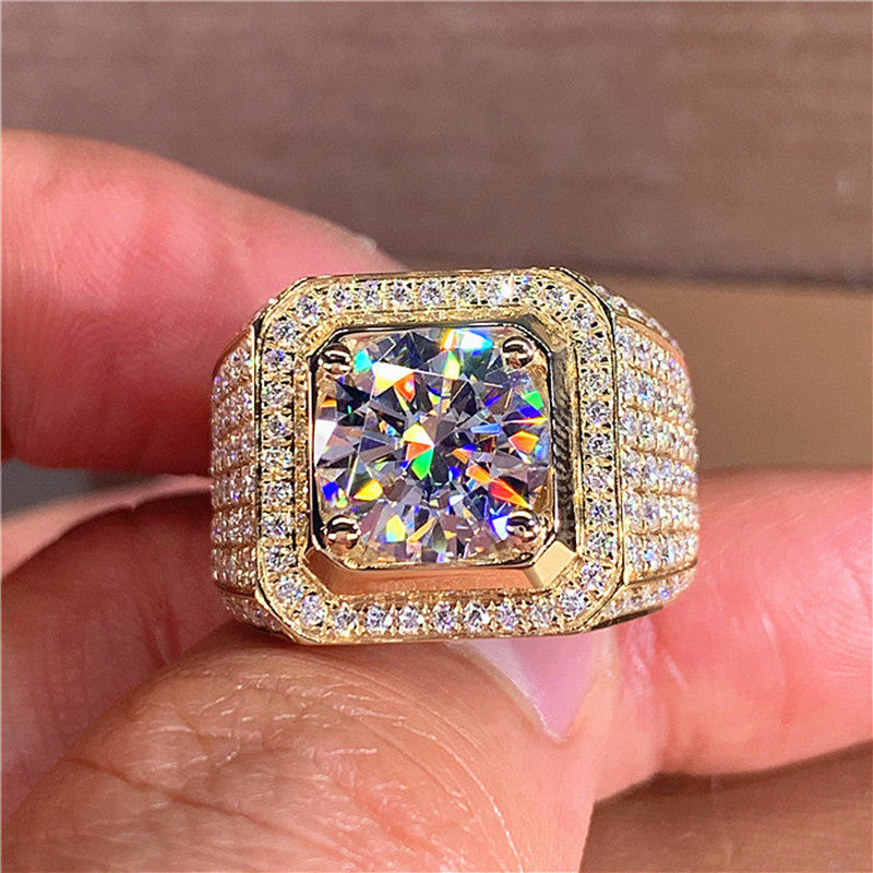 Gold tone ring with a large zircon held between fingers against a neutral background
