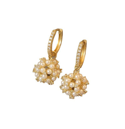 Gold earrings with pearl-like spherical designs on a white background