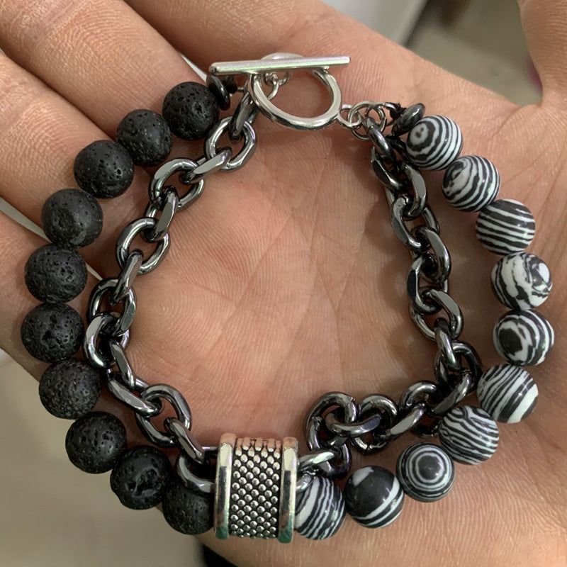 Bracelet with black beads, silver chain, and striped beads on a hand.