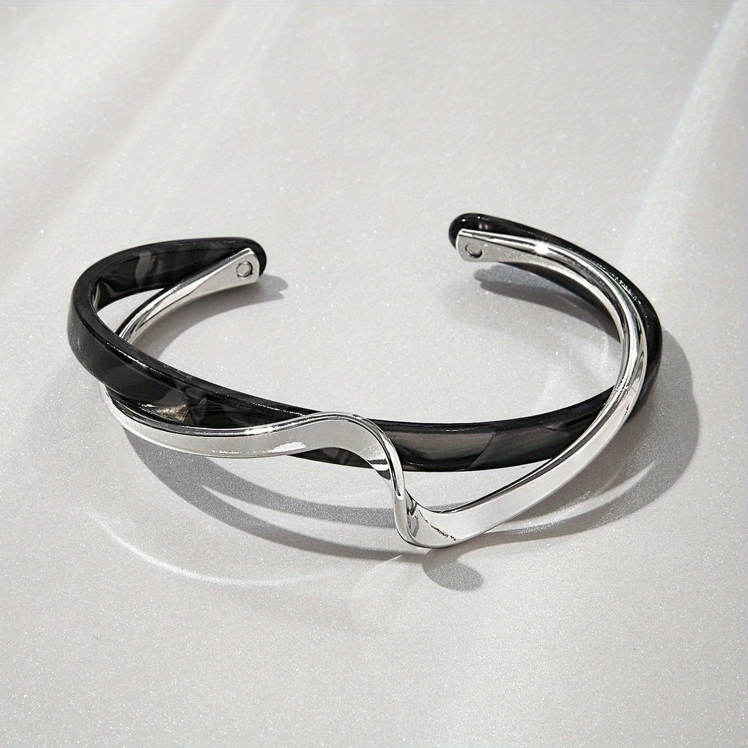 Silver and black bracelet on a light gray background