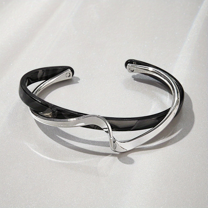 Silver and black bracelet on a light gray background