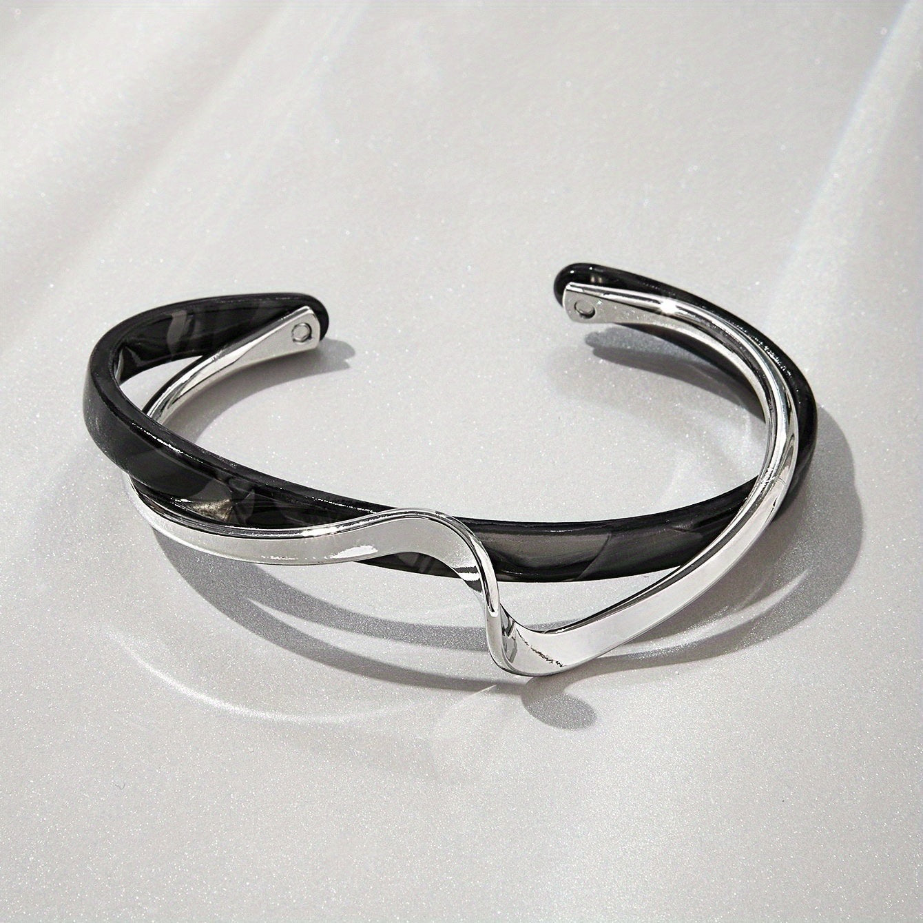 Silver and black bracelet on a light gray background