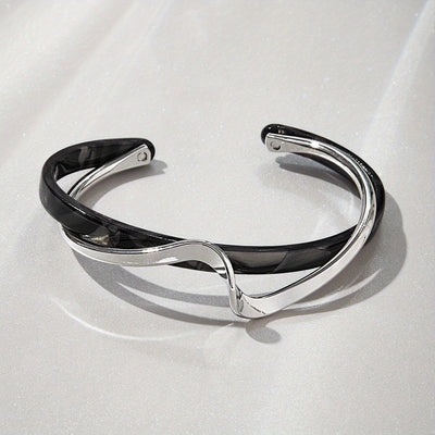 Silver and black bracelet on a light gray background