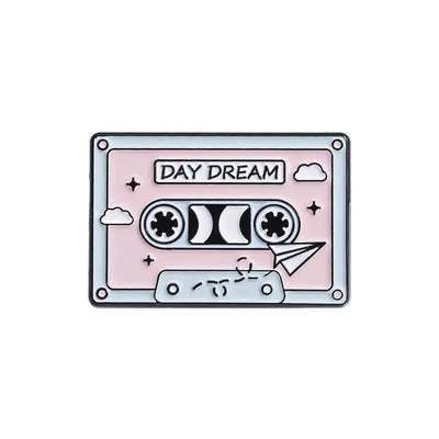 Cassette tape design enamel pin with 'Day Dream' text on a light pink background