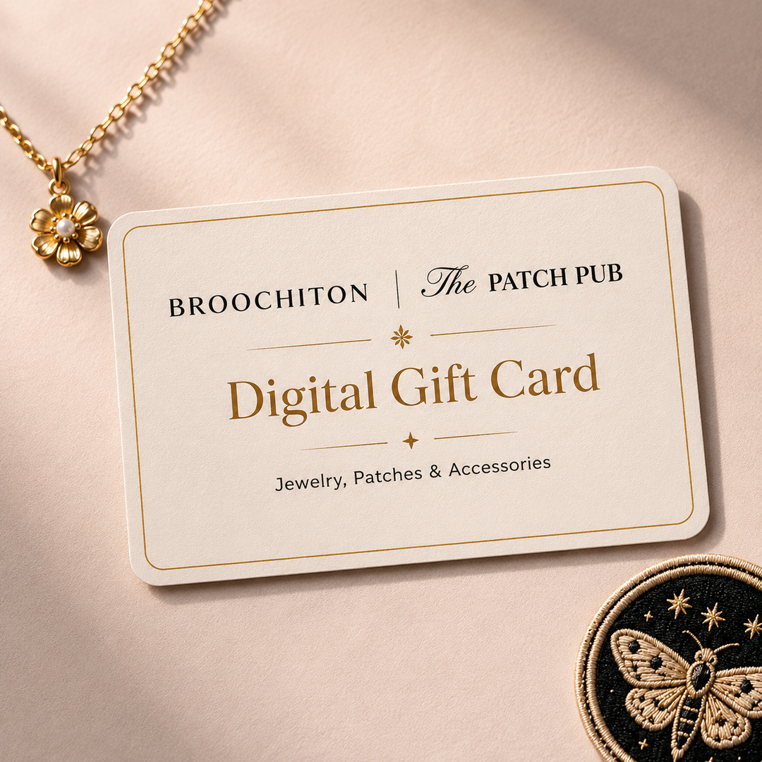 A cream-colored Broochiton x The Patch Pub digital gift card with gold lettering, styled on a warm beige background with a gold flower necklace and a black embroidered patch nearby.