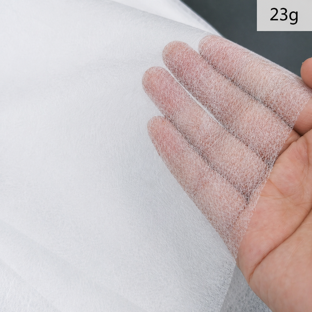 Close-up of a hand holding a Fusible Interlining Fabric with a visible weight label &